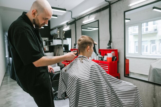 Il barbiere fa un'acconciatura per un giovane seduto su una sedia in attesa del completamento di un taglio di capelli