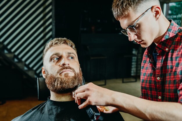 Il barbiere si taglia la barba a un uomo nel salone