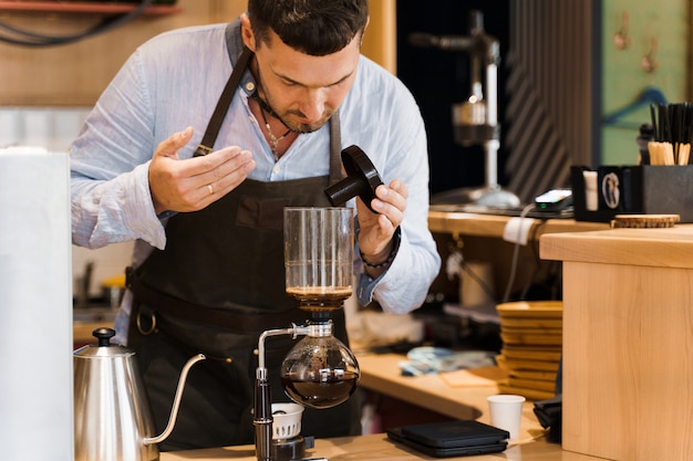 Il barista annusa caffè aromatizzato nel dispositivo a sifone