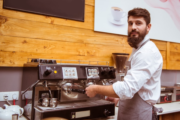 Il barista barbuto prepara il caffè per un cliente.