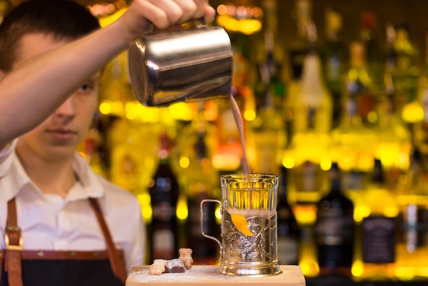 Il barista che prepara cocktail in un bar della discoteca. Versare il cocktail nel bicchiere..