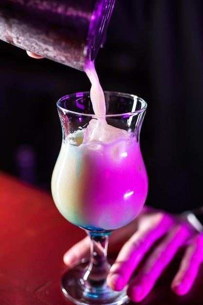 Il barista del primo piano prepara un cocktail alcolico con ghiaccio Miscelazione di cocktail alcolici nel ristorante pub discoteca Illuminazione rosa atmosferica su sfondo nero