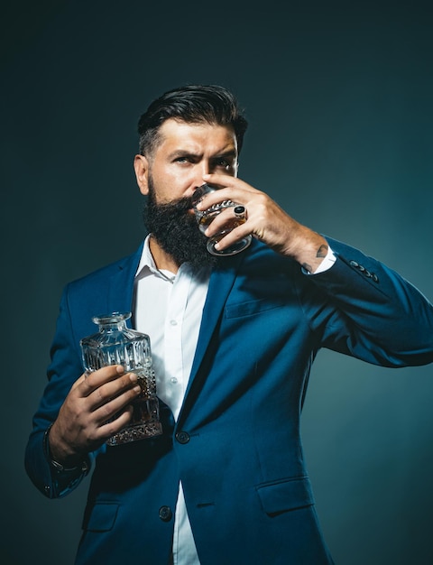 Il barista dell'uomo di concetto di stile di moda con la barba tiene il sommelier del brandy di vetro ha un sapore costoso dell'alcool...