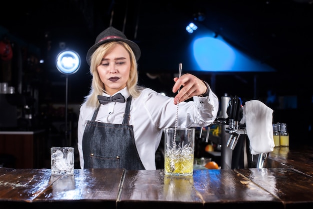 Il barista della ragazza mescola un cocktail nella sala pubblica