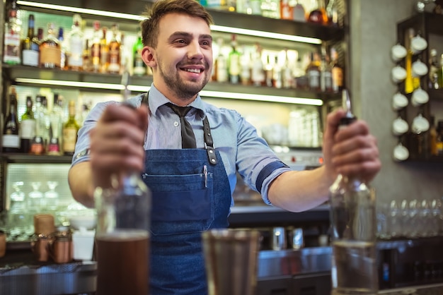 Il barista felice che prepara un cocktail al bar