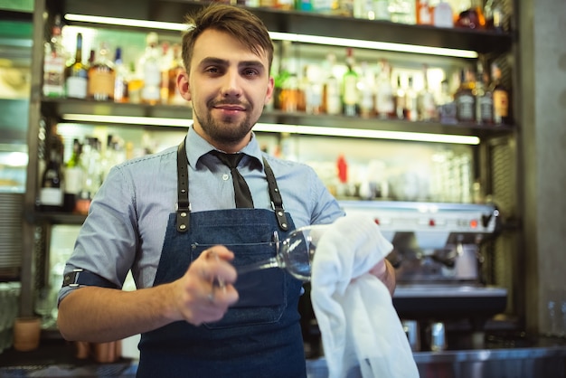 Il barista felice che pulisce il bicchiere del bar