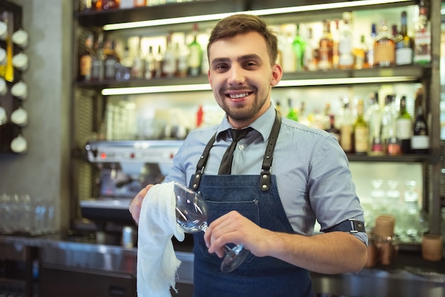 Il barista felice che pulisce il bicchiere del bar