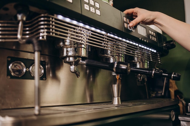 Il barista femminile sta pressando la polvere di caffè macinato fresco espresso in un supporto di metallo che produce caffeina