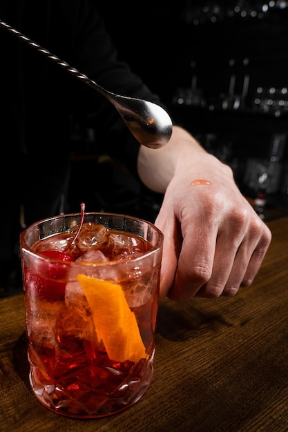 Il barista gli mette in mano una goccia di cocktail alcolico Negroni e lo assaggia Il barista prepara il classico cocktail Negroni al bar