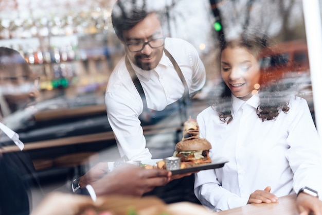 Il barista ha portato un hamburger per una coppia che siede in un bar.