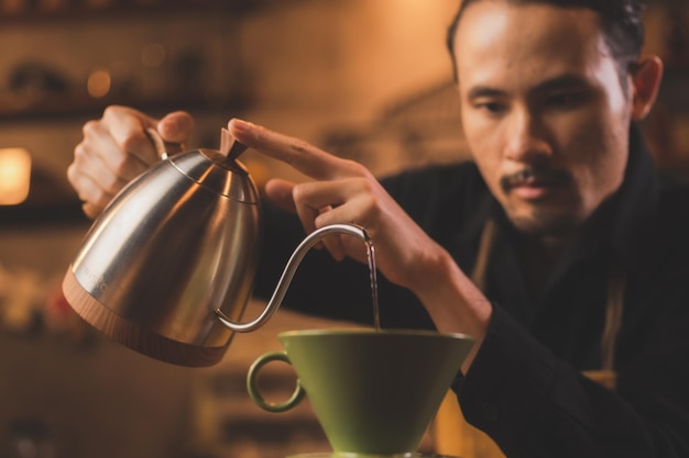 Il barista hipster asiatico che lavora per fare un caffè con il filtro del caffè con processo lento o la birra a goccia è una bevanda calda in stile vintage con caffeina dall'aroma fresco e servita su un aromatico nero scuro