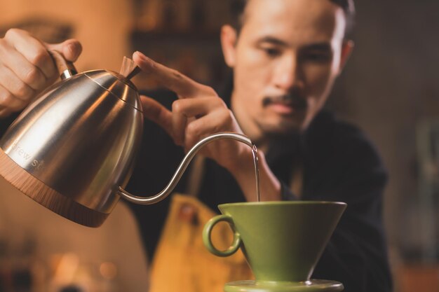 Il barista hipster asiatico che lavora per fare un caffè con il filtro del caffè con processo lento o la birra a goccia è una bevanda calda in stile vintage con caffeina dall'aroma fresco e servita su un aromatico nero scuro