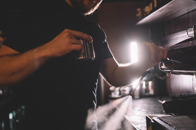 Il barista sta lavando la macchina del caffè e tiene in mano la brocca