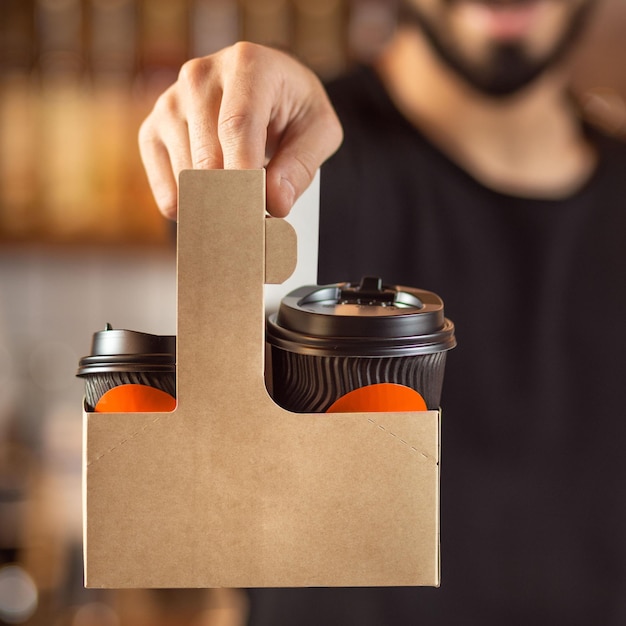 Il barista sta lavorando in una caffetteria tenendo una tazza di caffè da asporto