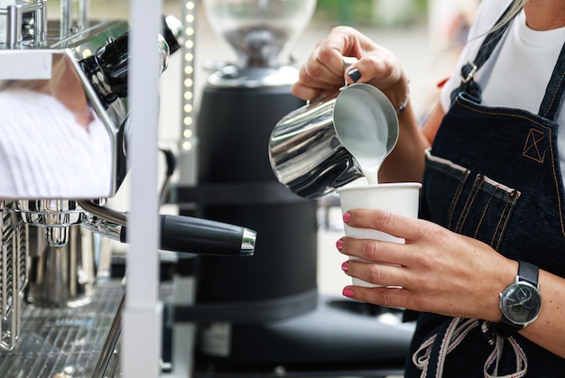 Il barista sta preparando il caffè. Latte fumante e schiumogeno per cappuccino o latte.