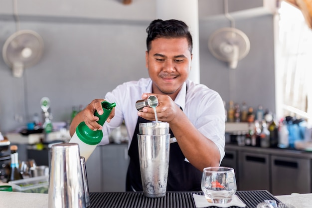 Il barista sta preparando un cocktail al bancone del bar.