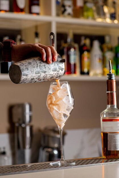 Il barista sta preparando un cocktail al bar La mano del barista sta versando un cocktail già pronto in un bicchiere