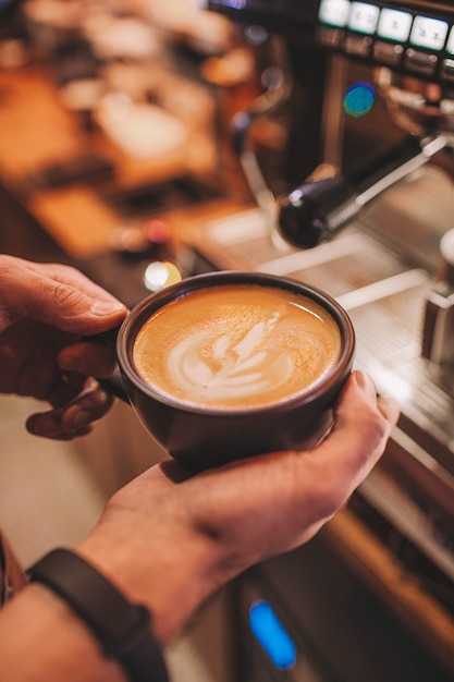 Il barista tiene una tazza di caffè nelle sue mani