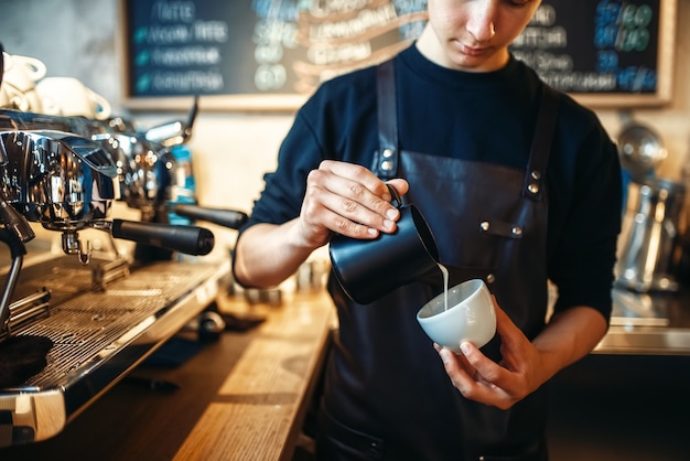 Il barista versa la panna nella tazza di caffè