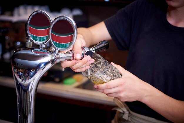 Il barman versa la birra nella tazza dal rubinetto.