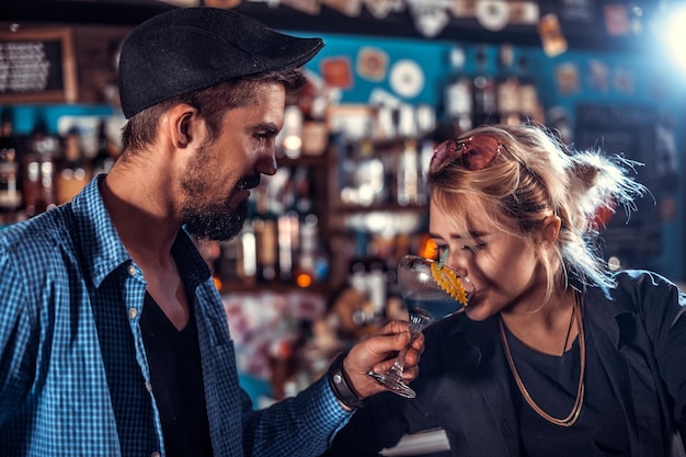 Il bartending ragazza focalizzato decora intrugli colorati mentre si trova vicino al bancone del bar nel bar