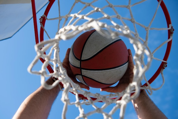 Il basket come simbolo sportivo e di fitness di un'attività di svago di squadra che gioca. Pallacanestro che passa attraverso il canestro sul cielo.