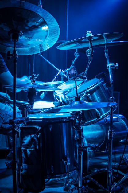 Il batterista suona la batteria, vista laterale, con illuminazione da concerto blu