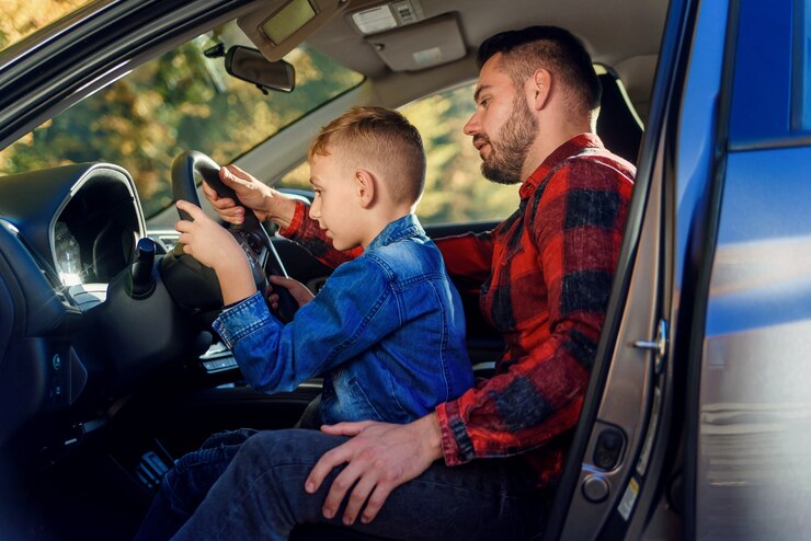 Il bel padre che indica qualcosa mentre insegna al figlio adolescente a guidare l'auto