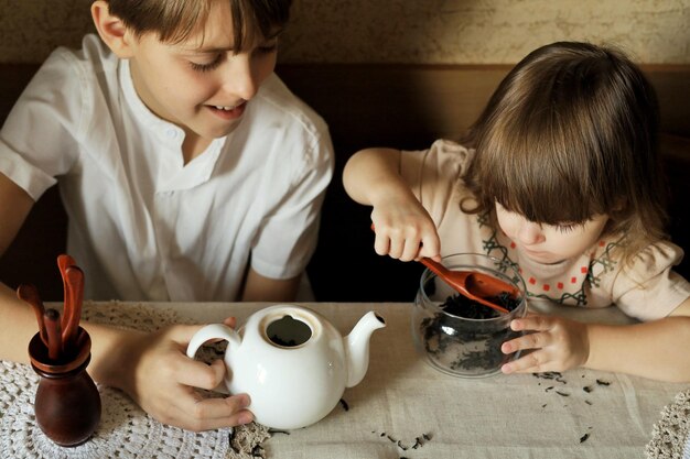 Il bel ragazzo e la sua simpatica sorellina sono seduti al tavolo della cucina a casa e preparano il tè