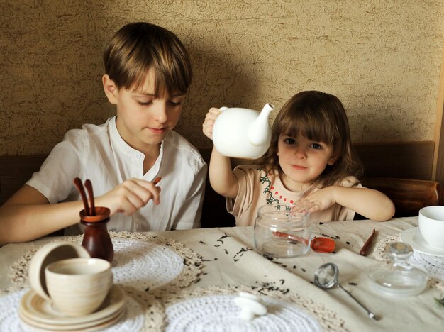 Il bel ragazzo e la sua simpatica sorellina sono seduti al tavolo della cucina a casa e preparano il tè