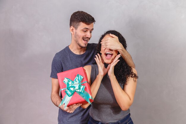 Il bel ragazzo sta coprendo gli occhi della sua ragazza e gli sta facendo un regalo.