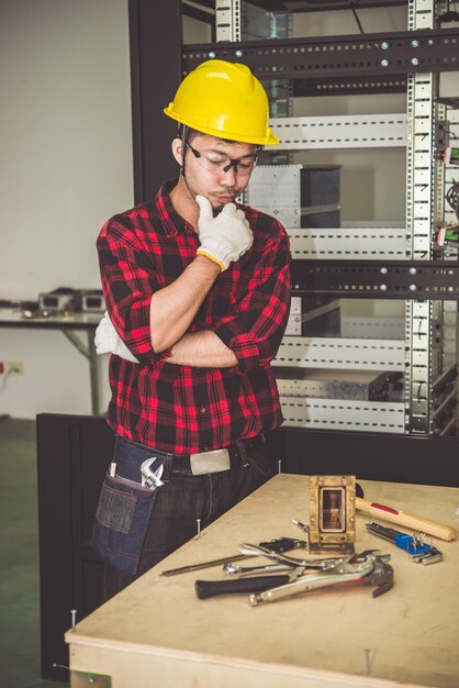 Il bel tecnico asiatico lavora sulla scrivania con gli strumentiLa gente tailandese ripara il prodottoConcetto di festa del lavoro