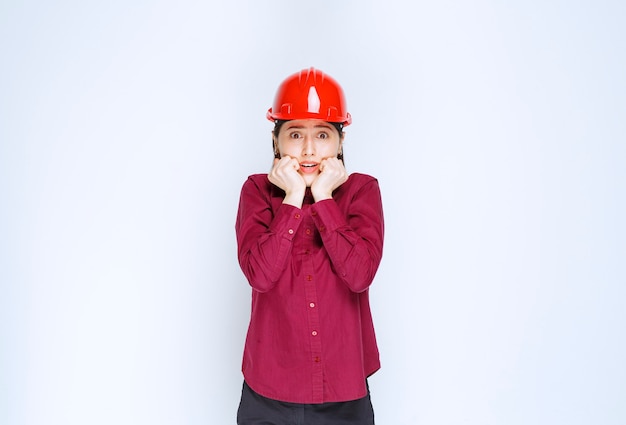 Il bello architetto femminile in casco duro rosso ha paura di qualcosa.