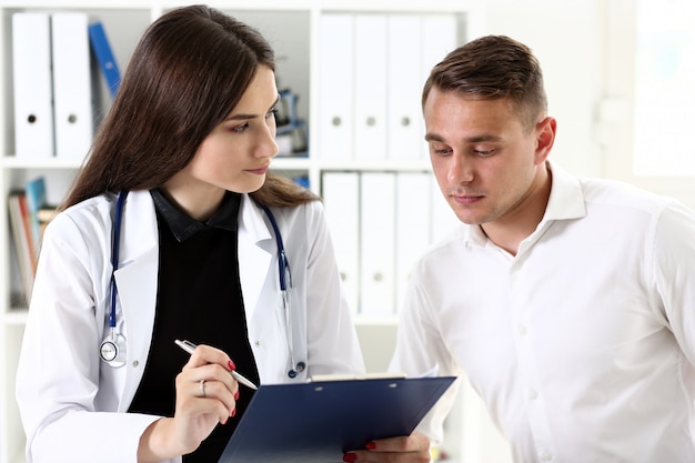 Il bello medico femminile sorridente della medicina spiega la diagnosi