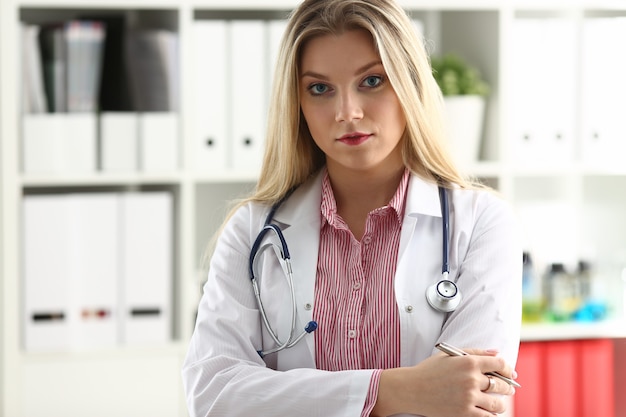 Il bello medico femminile sorridente si siede al posto di lavoro