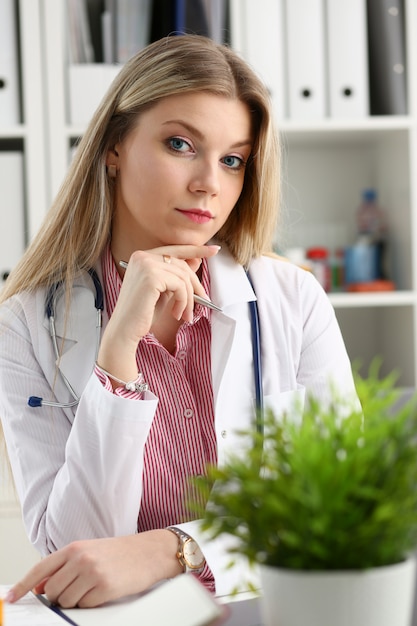 Il bello medico femminile sorridente si siede nel luogo di lavoro