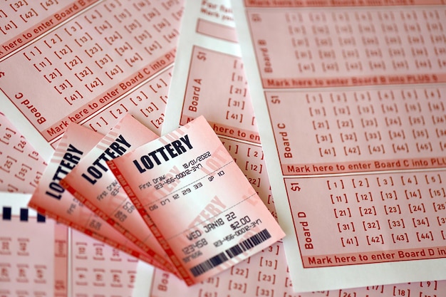 Il biglietto della lotteria rosso si trova su fogli di gioco rosa con numeri per la marcatura per giocare alla lotteria Concetto di gioco della lotteria o dipendenza dal gioco Primo piano