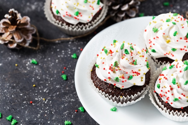 Il bigné del cioccolato ha decorato la crema bianca e gli abeti su un fondo scuro. Dolci natalizi. Dessert di Capodanno