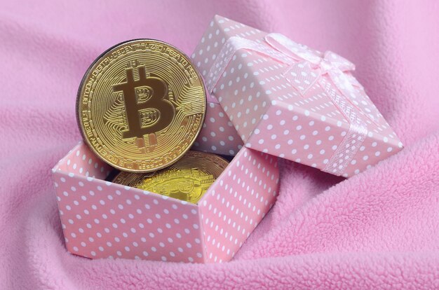Il bitcoin d&#39;oro si trova in una piccola scatola regalo rosa con un piccolo fiocco