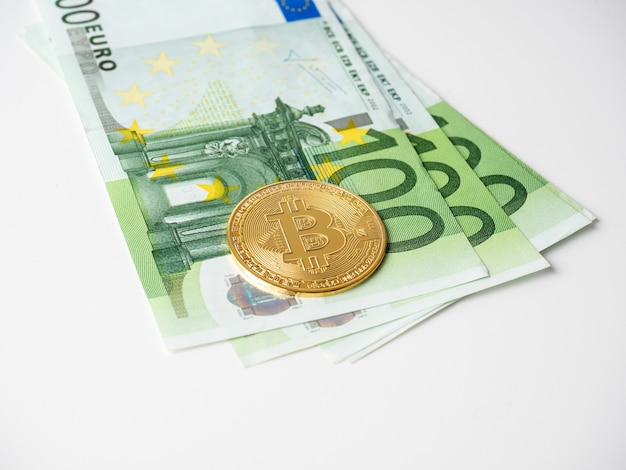 Il bitcoin dorato è sulle banconote da cento euro. Sfondo bianco. Vista laterale. Concetto di criptovaluta