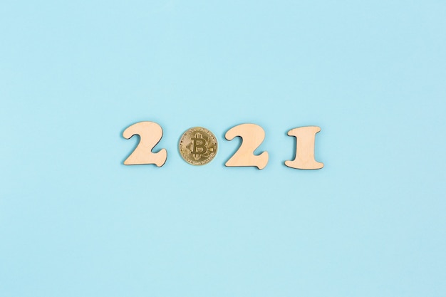 Il bitcoin in oro e i numeri in legno 2021 si trovano su una superficie blu