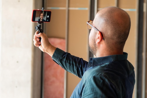 Il blogger vlogger dell'uomo registra un film selfie sul suo smartphone all'aperto guardando la telecamera parlare in video