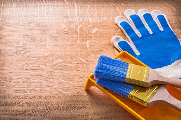 Il bordo di legno con i guanti protettivi dipinge il concetto della costruzione del vassoio e delle spazzole