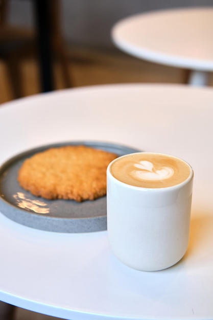 Il brunch mattutino nella caffetteria è sul tavolo Biscotto gigante e cappuccino con una bella schiuma di latte