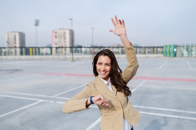 Il brunette caucasico attraente si è vestito in rivestimento beige che si leva in piedi sul parcheggio e che fluttua al tassista.