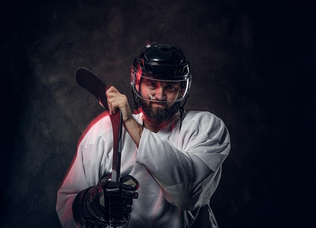 Il brutale giocatore di hockey barbuto posa per il fotografo e la luce rossa crea un effetto di movimento.