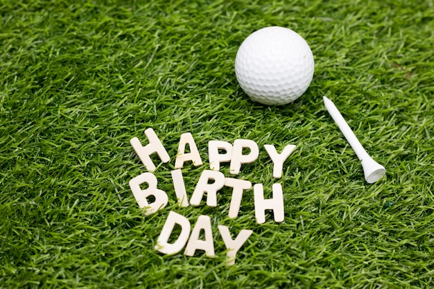 Il buon compleanno con palla da golf e il T è su erba verde