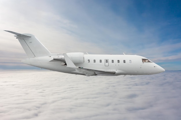 Il business jet esecutivo di lusso moderno bianco vola nell'aria sopra le nuvole
