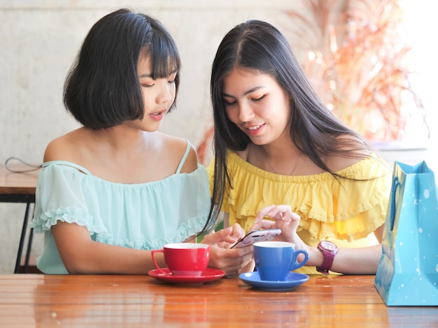 Il caffè bevente della donna asiatica e si rilassa nel caffè della caffetteria