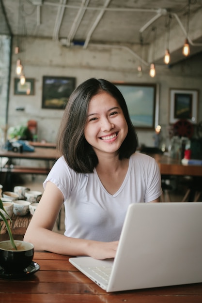 Il caffè bevente della donna asiatica e si rilassa nel caffè della caffetteria